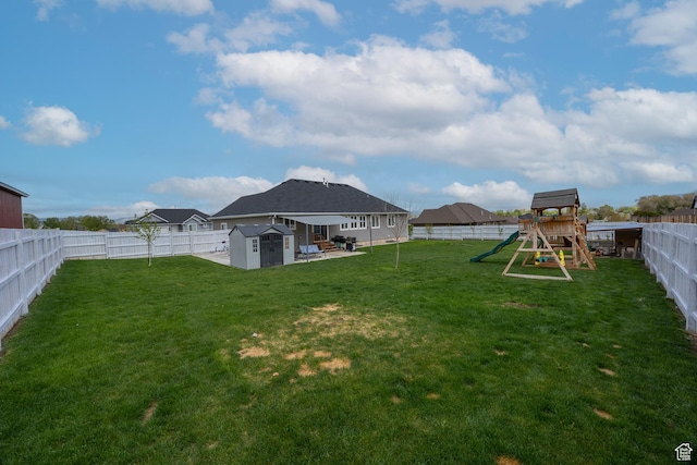 view of yard featuring a storage shed, a playground, an outdoor structure, and a patio