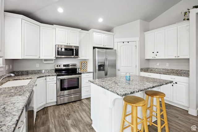 kitchen featuring stainless steel appliances, a sink, vaulted ceiling, a kitchen island, and recessed lighting