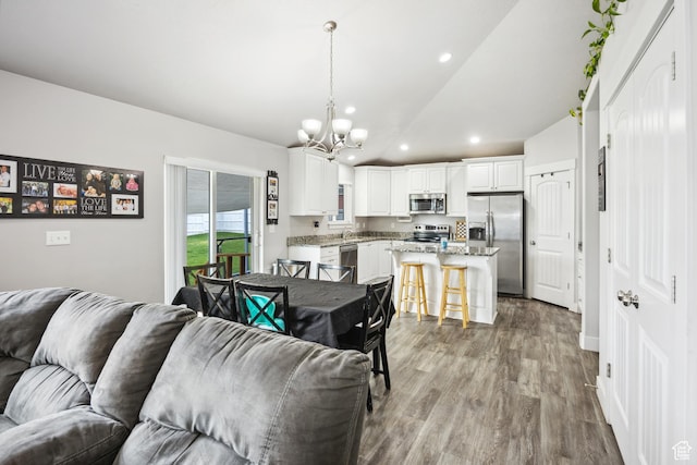 living area featuring a chandelier, recessed lighting, wood finished floors, and lofted ceiling