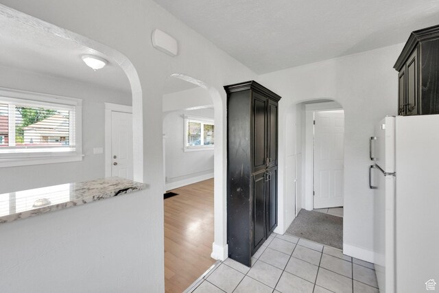 815 E 22nd St, Ogden, UT 84401 - kitchen with freestanding refrigerator, light stone counters, arched walkways, baseboards, and light tile patterned floors