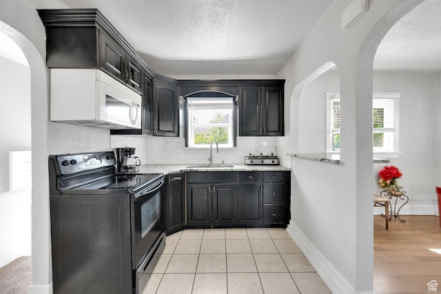 815 E 22nd St, Ogden, UT 84401 - kitchen with black electric range oven, white microwave, a sink, arched walkways, and healthy amount of natural light