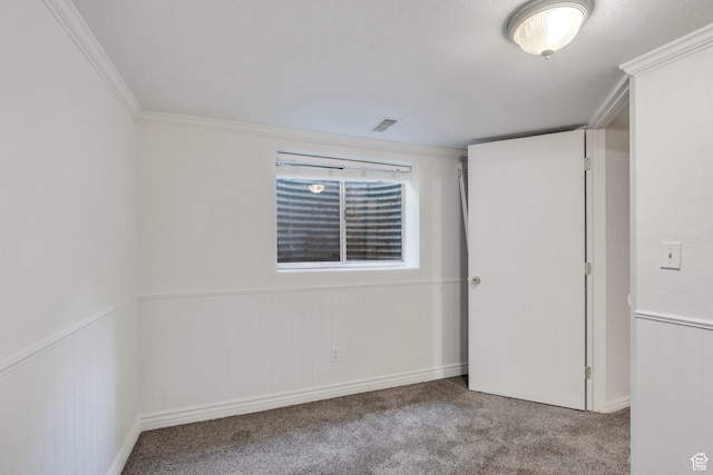 carpeted empty room featuring crown molding and baseboards