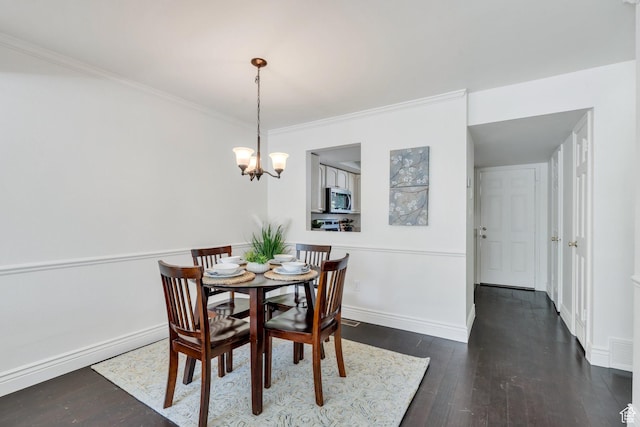 dining space featuring wood finished floors, a chandelier, crown molding, and baseboards