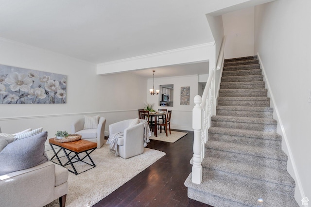 living area featuring wood finished floors, stairs, ornamental molding, and a chandelier