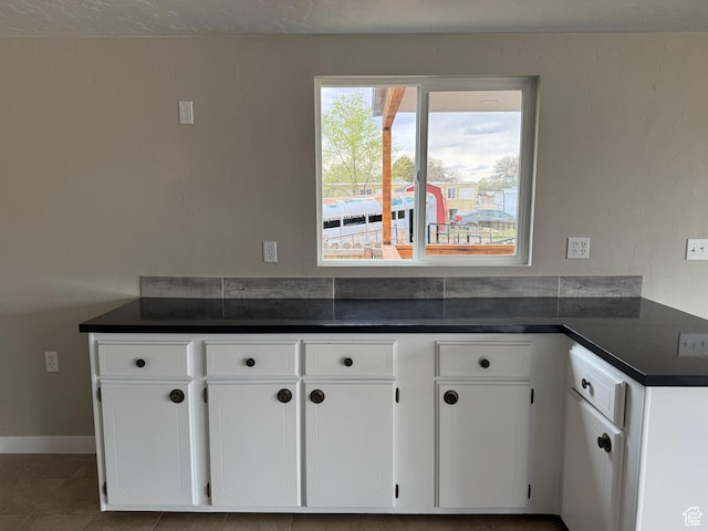 22 S 400 E, Myton, UT 84052 - kitchen with dark countertops, white cabinetry, tile patterned floors, and baseboards