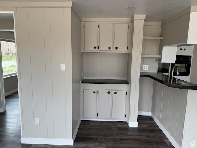 22 S 400 E, Myton, UT 84052 - kitchen with dark countertops, dark wood-style floors, black oven, white cabinetry, and baseboards