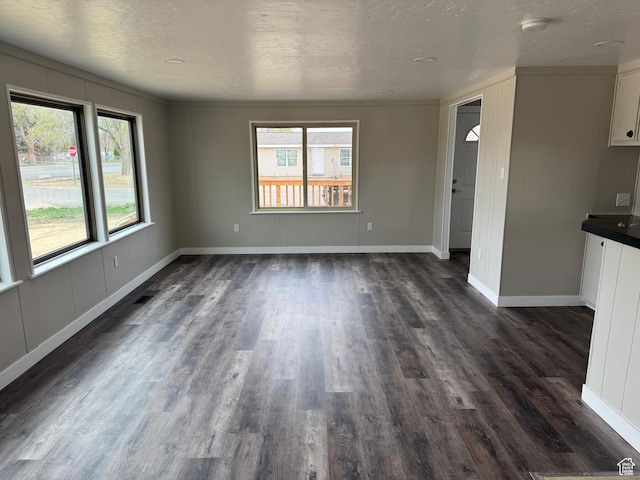 22 S 400 E, Myton, UT 84052 - unfurnished living room featuring plenty of natural light, dark wood-style floors, a decorative wall, baseboards, and a textured ceiling