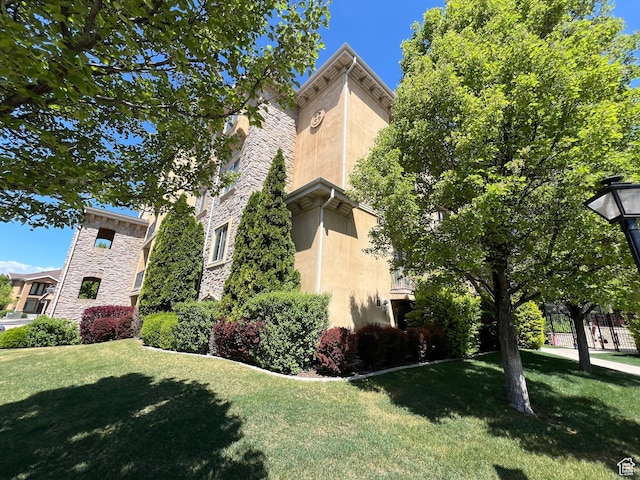 view of home's exterior featuring stucco siding, a lawn, and stone siding