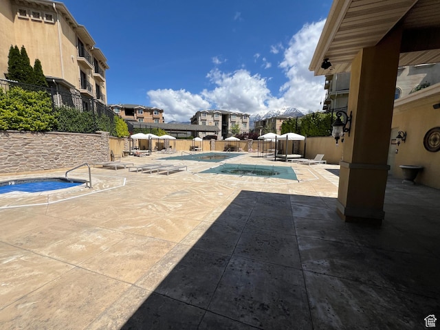 view of patio / terrace featuring a community hot tub, a community pool, fence, and a residential view