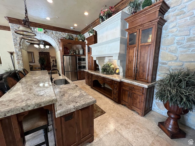kitchen with stainless steel appliances, a sink, arched walkways, light stone countertops, and a chandelier
