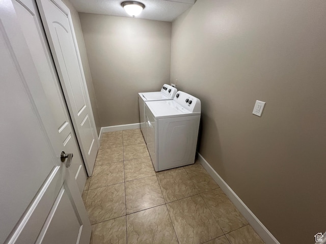 laundry area featuring washer and dryer, baseboards, and light tile patterned flooring