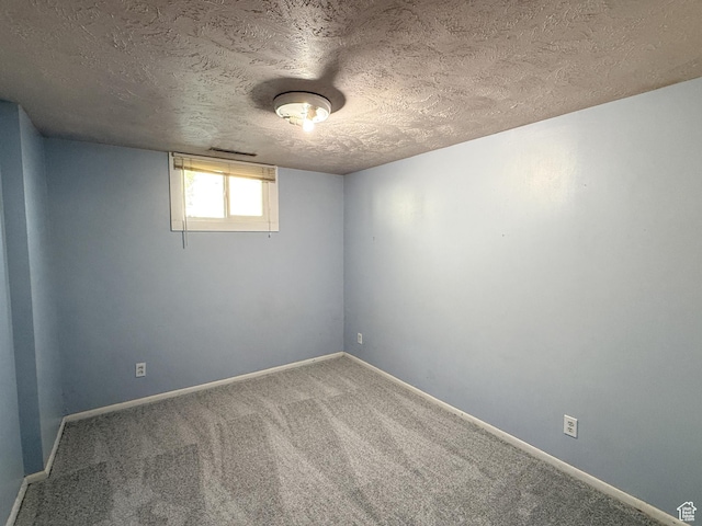 empty room featuring a textured ceiling, carpet, and baseboards