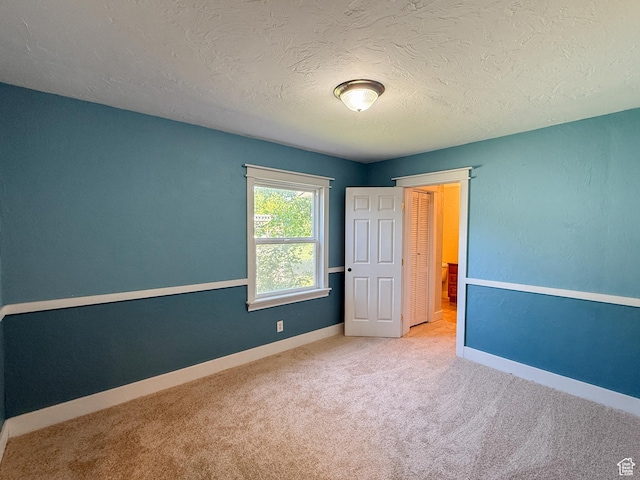 spare room with carpet flooring, a textured ceiling, and baseboards
