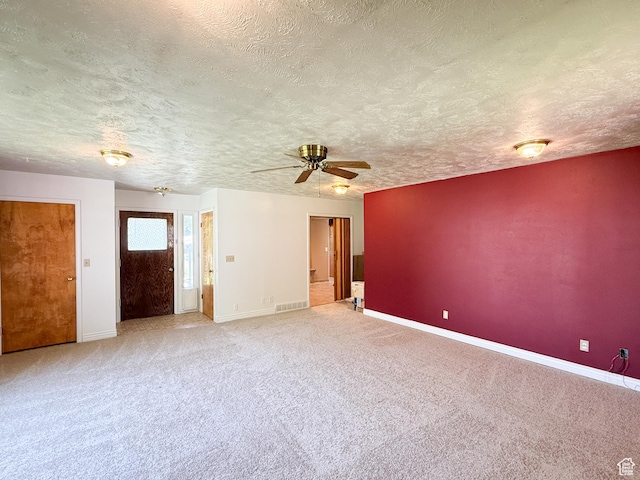 spare room featuring a textured ceiling, carpet flooring, baseboards, and a ceiling fan