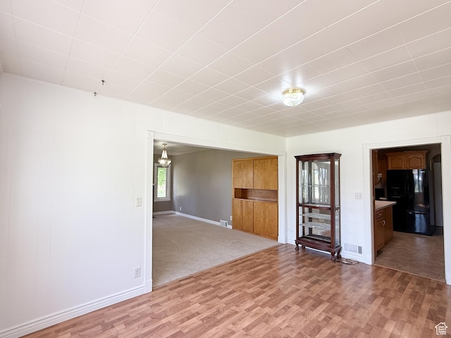 unfurnished living room with light wood-type flooring and baseboards
