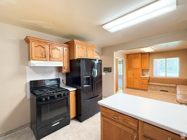 kitchen with black appliances, under cabinet range hood, light countertops, and baseboards