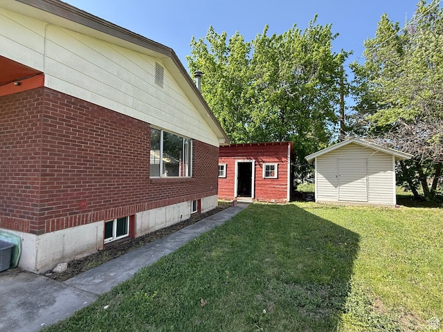 view of home's exterior featuring a yard, brick siding, and an outbuilding