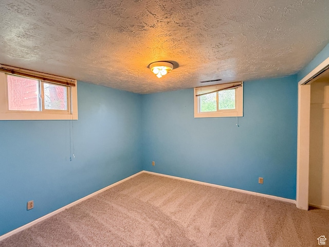 basement featuring carpet, baseboards, and a textured ceiling