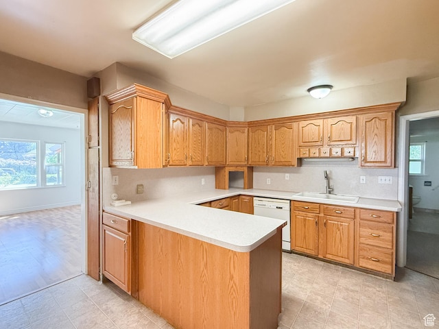 kitchen with a sink, white dishwasher, light countertops, and plenty of natural light