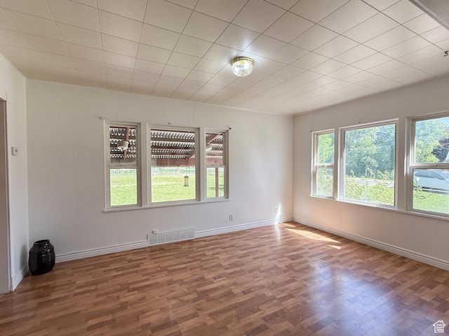 spare room with healthy amount of natural light, wood finished floors, and baseboards