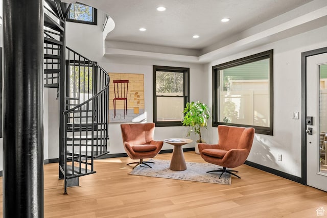 sitting room featuring wood finished floors, baseboards, stairs, recessed lighting, and a tray ceiling