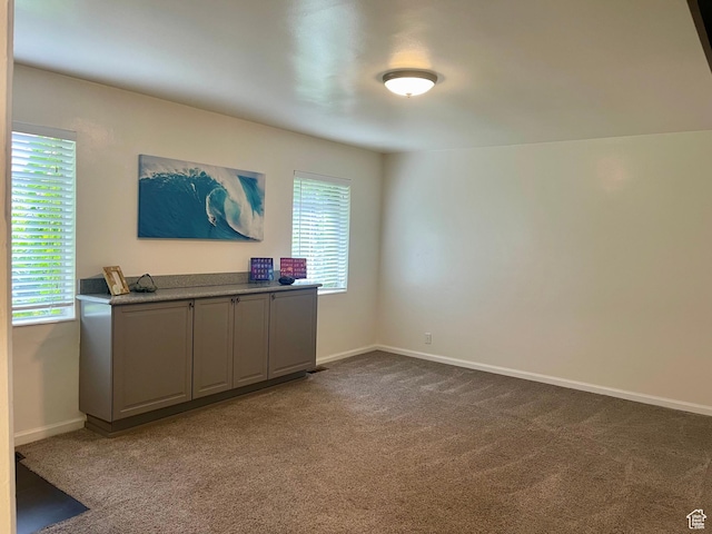 interior space featuring dark colored carpet and baseboards