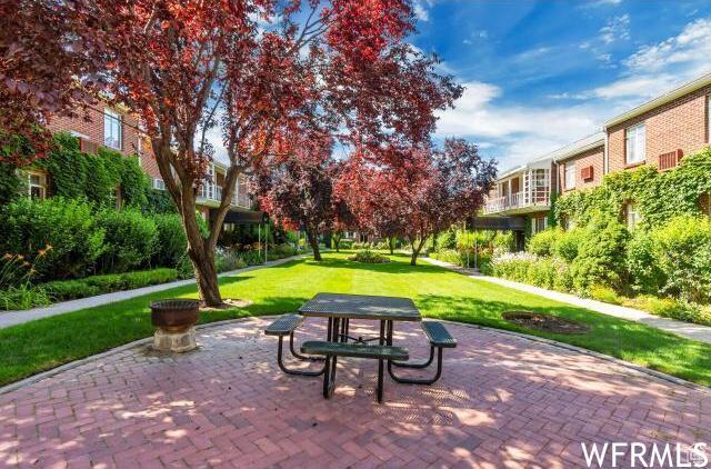 view of property's community featuring a lawn and a patio