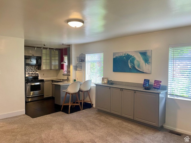 kitchen featuring stainless steel electric range, black microwave, dark carpet, and a sink