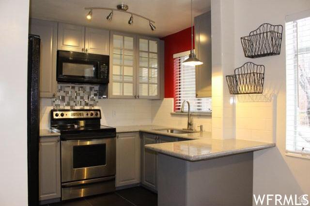 kitchen featuring electric stove, black microwave, a sink, a peninsula, and healthy amount of natural light