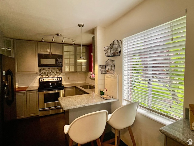 kitchen with black appliances, a sink, a peninsula, tasteful backsplash, and hanging light fixtures