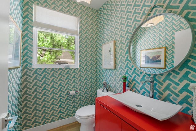1863 E Hubbard Ave, Salt Lake City, UT 84108 - bathroom with wallpapered walls, toilet, a sink, wood finished floors, and baseboards