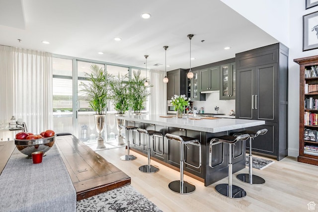 268 S State St E Unit 417, Salt Lake City, UT 84111 - kitchen with light wood finished floors, a breakfast bar area, glass insert cabinets, pendant lighting, and a kitchen island