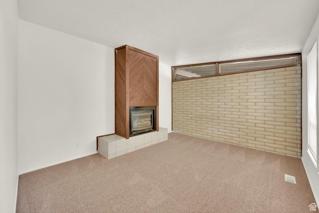 unfurnished living room featuring a fireplace, carpet floors, and brick wall