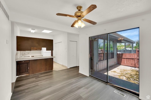 unfurnished living room with light wood-style flooring, a ceiling fan, baseboards, and a sink