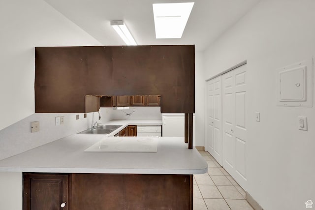 kitchen with a sink, light countertops, light tile patterned floors, a peninsula, and white electric stovetop