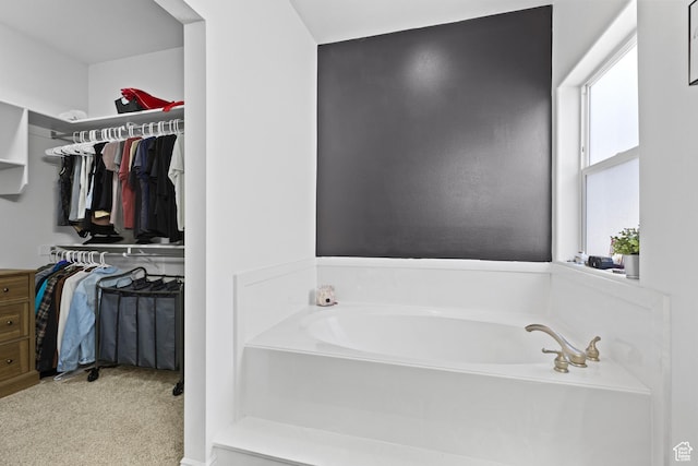 full bathroom with a spacious closet and a bath