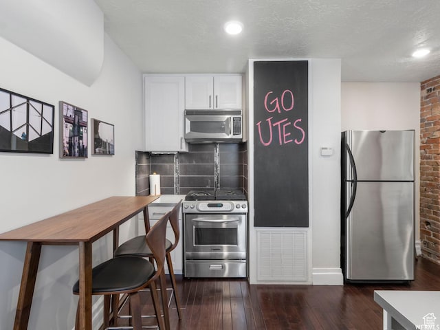 1318 E 300 S, Salt Lake City, UT 84102 - kitchen with appliances with stainless steel finishes, white cabinetry, decorative backsplash, dark wood finished floors, and brick wall