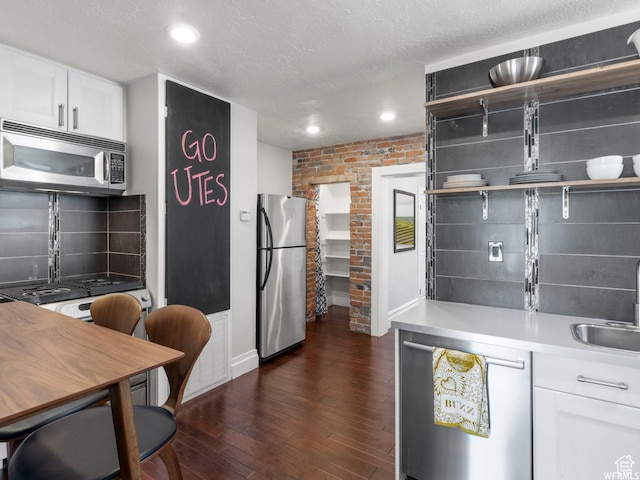 1318 E 300 S, Salt Lake City, UT 84102 - kitchen with appliances with stainless steel finishes, a sink, dark wood-style flooring, white cabinetry, and decorative backsplash