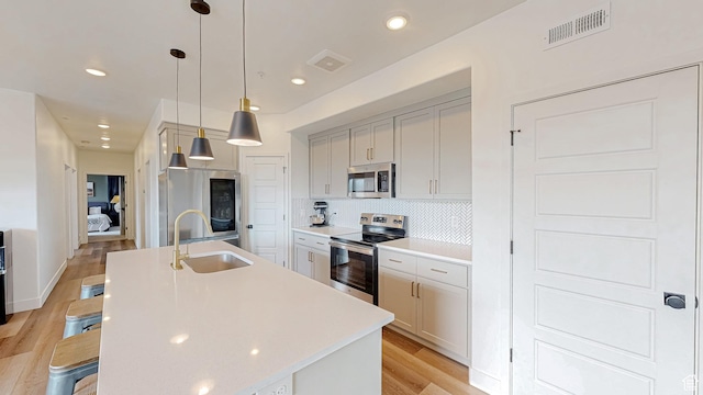 376 S 1080 W Unit 301, American Fork, UT 84003 - kitchen featuring stainless steel appliances, a sink, light wood-style flooring, a kitchen island with sink, and light countertops