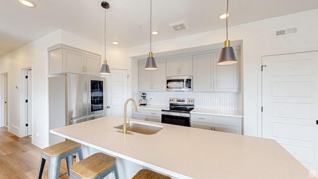 376 S 1080 W Unit 301, American Fork, UT 84003 - kitchen featuring appliances with stainless steel finishes, a sink, backsplash, a breakfast bar area, and light wood finished floors
