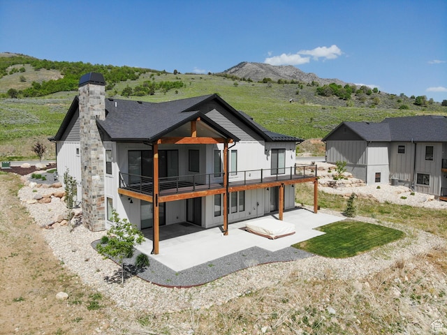 4491 N Seven Bridges Rd, Eden, UT 84310 - back of property with a patio, board and batten siding, a deck with mountain view, and a chimney