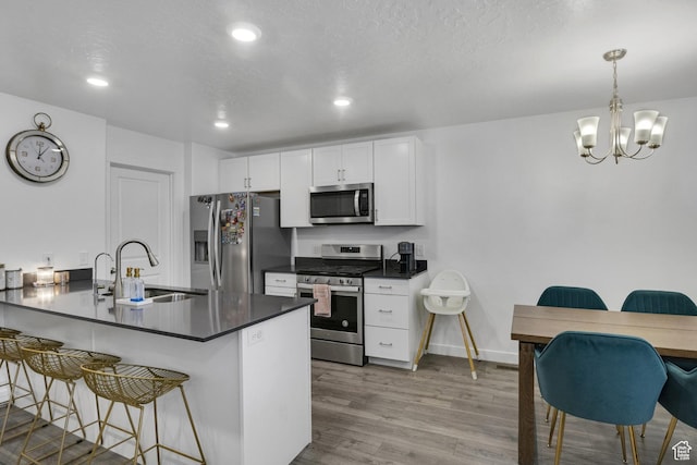 4013 W Cool Ave, Lehi, UT 84043 - kitchen with appliances with stainless steel finishes, a sink, dark countertops, a kitchen bar, and wood finished floors