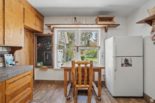 kitchen featuring freestanding refrigerator, open shelves, tile countertops, and dark wood-style flooring