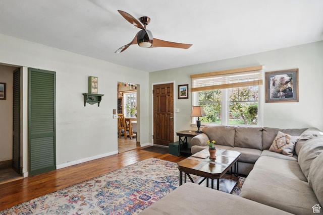 living room featuring wood finished floors, a ceiling fan, and baseboards