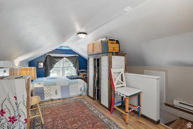 bedroom with wood finished floors, vaulted ceiling, and a baseboard heating unit