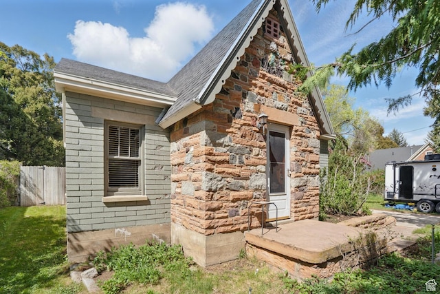 view of home's exterior with fence and roof with shingles