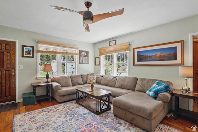 living area with wood-type flooring, a ceiling fan, and baseboards