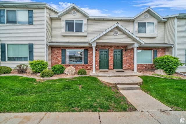 townhome / multi-family property featuring brick siding and a front lawn