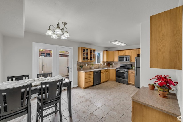 kitchen featuring appliances with stainless steel finishes, backsplash, a chandelier, light countertops, and a sink