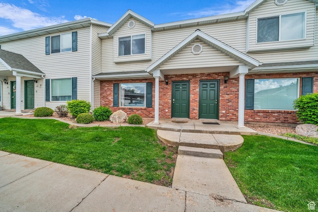 view of property with brick siding and a front lawn